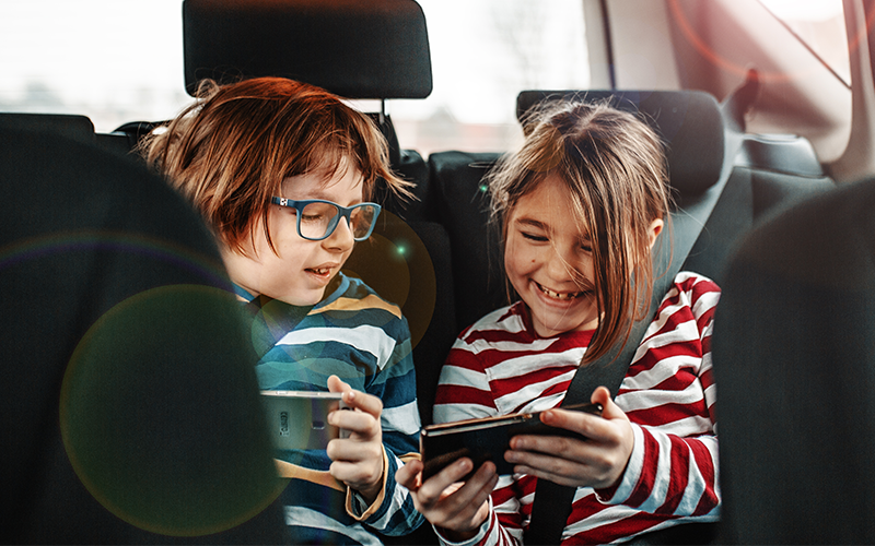 A boy and girl sitting in the car and wearing headphone